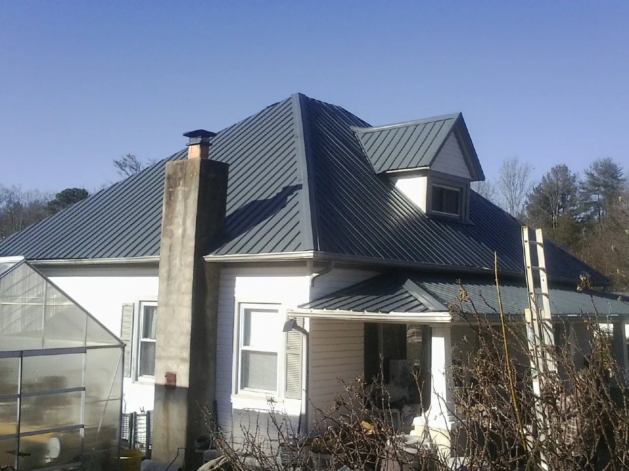 Dark blue standing seam metal roof on a white farmhouse with dormer — Slate & Tile Roof Repair by Roofing Brothers in Ft Mitchell