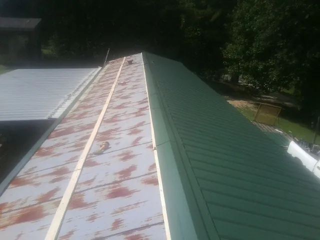 Old rusted panels beside newly installed green metal roofing — Wind Damage Roof Repair by Roofing Brothers in Ft Mitchell