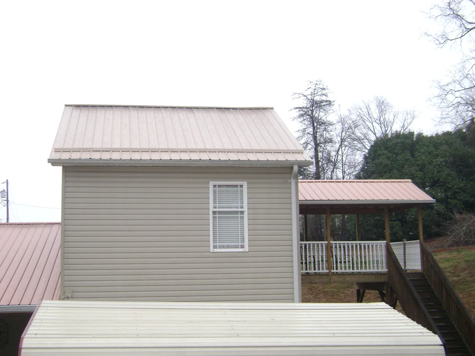 Tan metal roofs on a two story addition and attached porch, from a Roof Replacement job in Ft Mitchell
