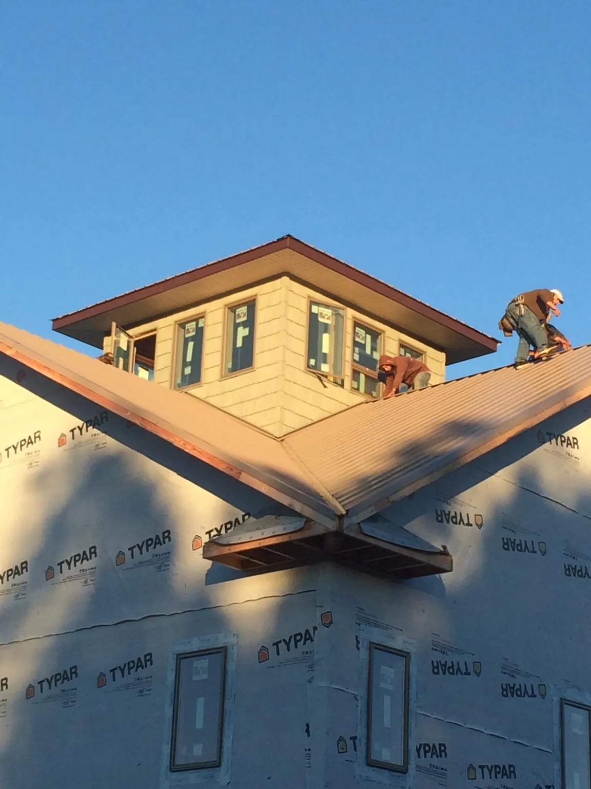Roofers working around a rooftop cupola on a new metal roof at sunset — Roof Waterproofing in Ft Mitchell by Roofing Brothers